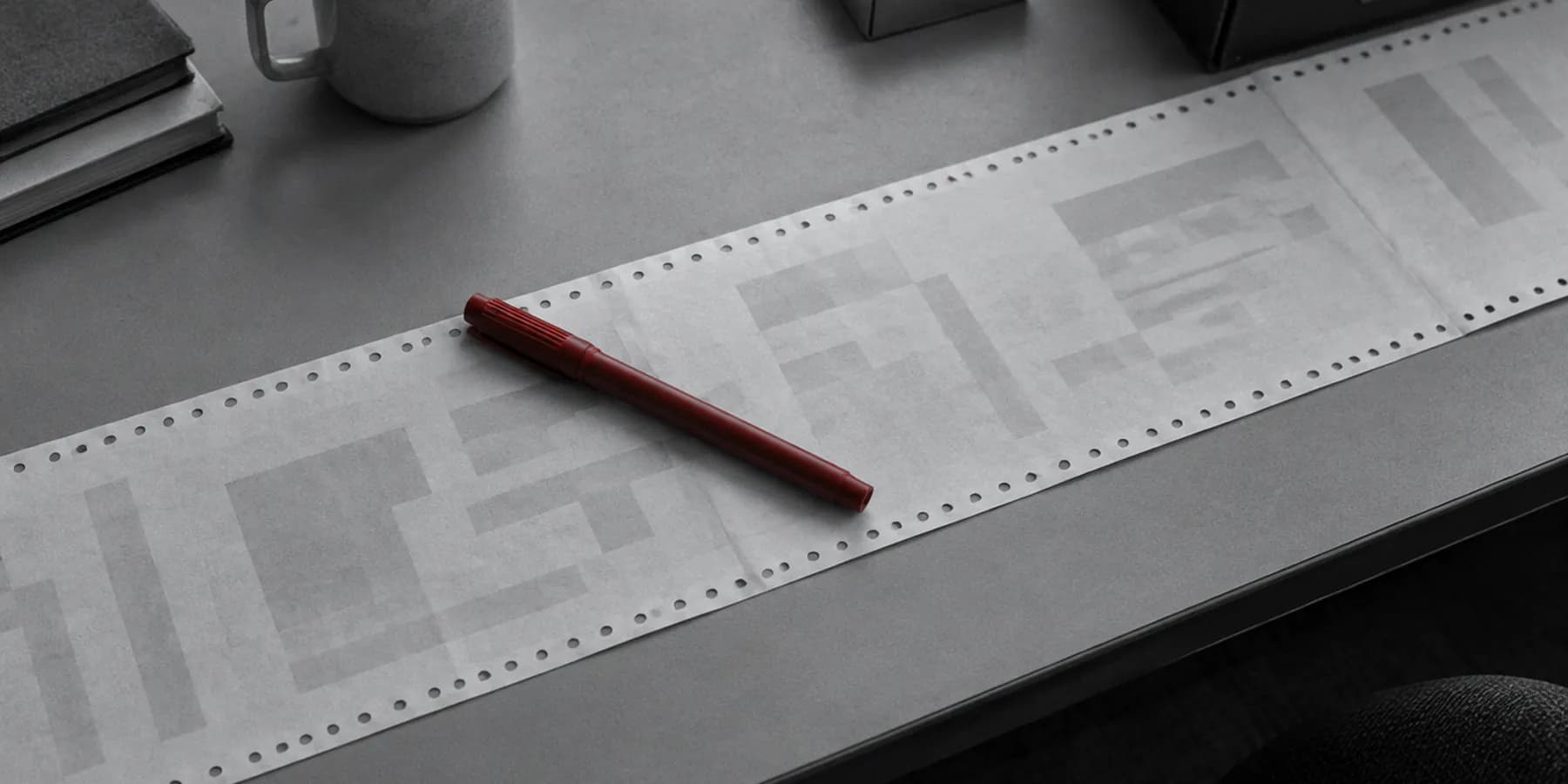 Papel continuo de impresora extendido sobre una mesa con un rotulador rojo encima